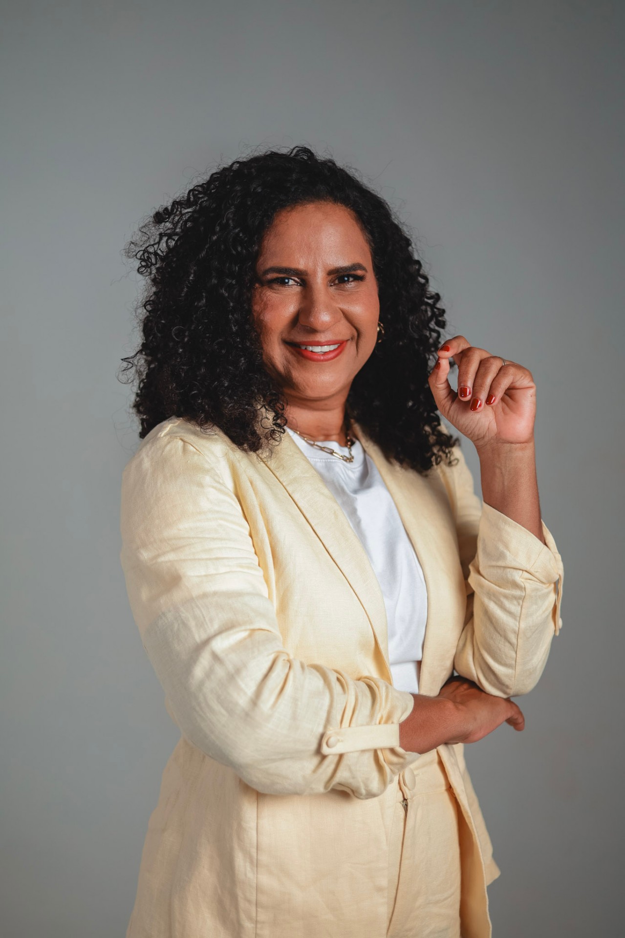 Retrato de Jacqueline Moraes sorrindo, de blazer amarelo claro